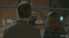 a man and a woman are standing in front of a fence with the words well we tried on the screen