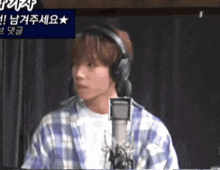 a young man wearing headphones stands in front of a microphone .