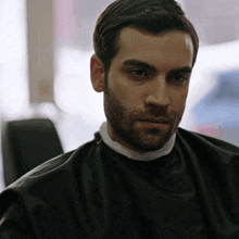 a man with a beard is getting his hair cut by a barber