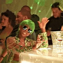 a woman with green hair is holding a glass of wine at a party