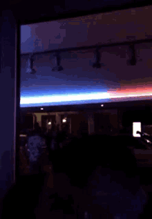 a crowd of people are gathered in a dark room with a red and blue light on the ceiling