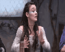 a woman in a white knitted sweater holds her hands out