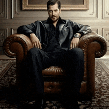 a man in a leather jacket is sitting in a leather chair