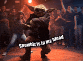 a group of people are dancing in a dark room with a caption that says " showbiz is in my blood "