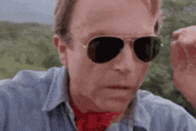a close up of a man wearing sunglasses and a red scarf .