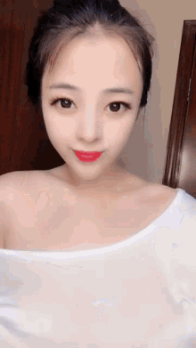 a woman wearing a white off the shoulder top is looking at the camera