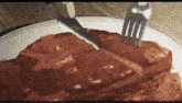 a person is cutting a piece of steak with a knife and fork .