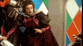 a woman in a red dress is standing next to a man in a knight 's costume .