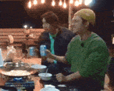two men are sitting at a table with bowls of food and a can of soda .