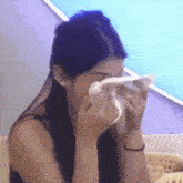 a woman is blowing her nose with a napkin while sitting down .