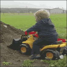 a little boy is sitting on a toy bulldozer
