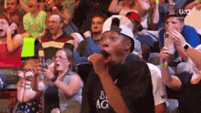 a man is singing into a microphone while wearing a shirt that says ' big ag ' on it