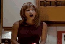 a woman in a red tank top is screaming with her mouth open