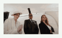 a man with a dreadlock on his head stands between two women in suits
