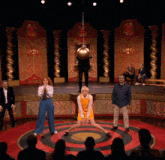 a group of people are standing in a circle on a stage in front of a target