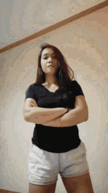 a woman in a black shirt and white shorts with her arms crossed