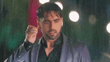 a man in a suit is standing in the rain and holding his jacket .