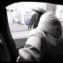 a person wearing a hoodie is sitting in a car looking out the window