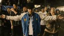 a man in a blue and white jacket is standing in a crowd of people .