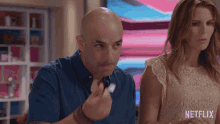 a man with a fork in his hand is standing next to a woman with netflix written on her shirt