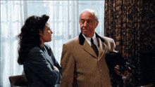a man in a suit and tie stands next to a woman