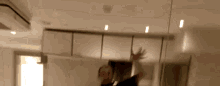a man is standing in front of a mirror in a room with his hands in the air .