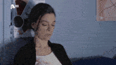 a woman is sitting in front of a wall with a hd logo on it