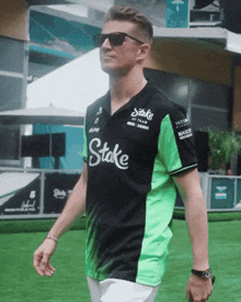 a man wearing a green and black shirt that says stake on it