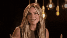 a woman with long blonde hair is looking at the camera