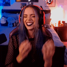 a woman with blue hair is wearing headphones and a black shirt