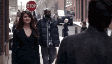 a woman walking down a street with a stop sign behind her