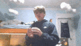 a boy wearing a blue nike hoodie stands in a bedroom