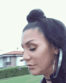 a close up of a woman 's face with a bun and earrings .