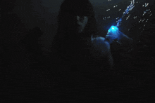 a woman blowing bubbles in the dark with a light behind her