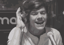 harry styles is wearing headphones and singing into a microphone in a black and white photo .