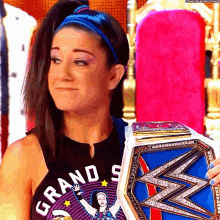 a woman wearing a shirt that says grand s is holding a championship belt