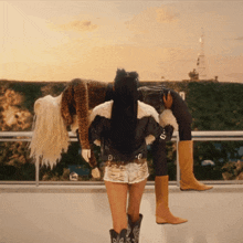 a woman wearing cowboy boots holds another woman 's leg