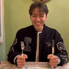 a man in a comme des garçons jacket holds a knife and fork