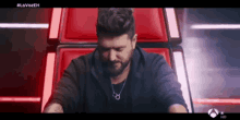 a man with a beard is sitting in a chair with his eyes closed