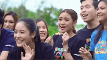 a group of people are smiling and clapping while wearing shirts that say i love you .
