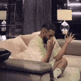 a man is sitting on a couch in a living room with his hands outstretched .