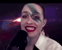a woman with makeup on her face is talking into a microphone .