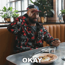 a man sitting at a table with a plate of food and the word okay written on it