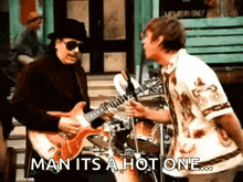a man is playing a guitar next to another man on a drum set .