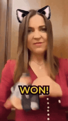 a woman wearing cat ears is holding a toy and the word won is on the screen