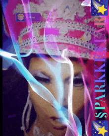 a woman wearing a pink hat is surrounded by blue and purple smoke and says sparkkissstar