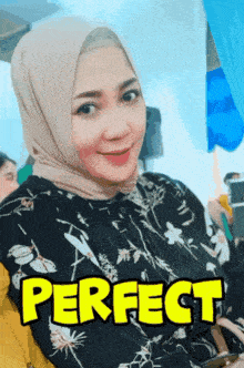 a woman wearing a hijab and a shirt that says perfect is smiling