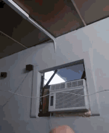 a white air conditioner is mounted to a white wall next to a window