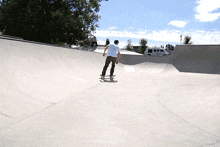 a man riding a skateboard down a ramp in a skate park