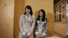 two girls are standing next to each other in front of a wall with posters on it .
